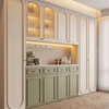 A built-in cabinetry unit in a modern room, featuring cream-colored arched upper cabinets with glass doors and warm under-cabinet lighting, paired with sage green lower cabinets and drawers on a light wood herringbone floor.